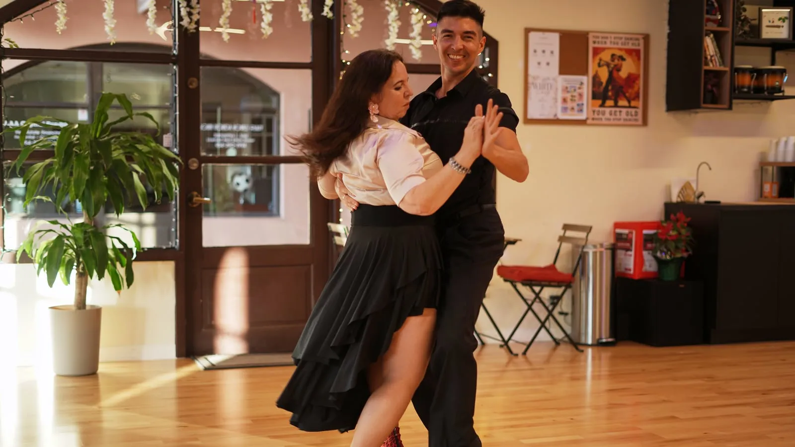 A couple in a close argentine tango embrace on the studio floor.
